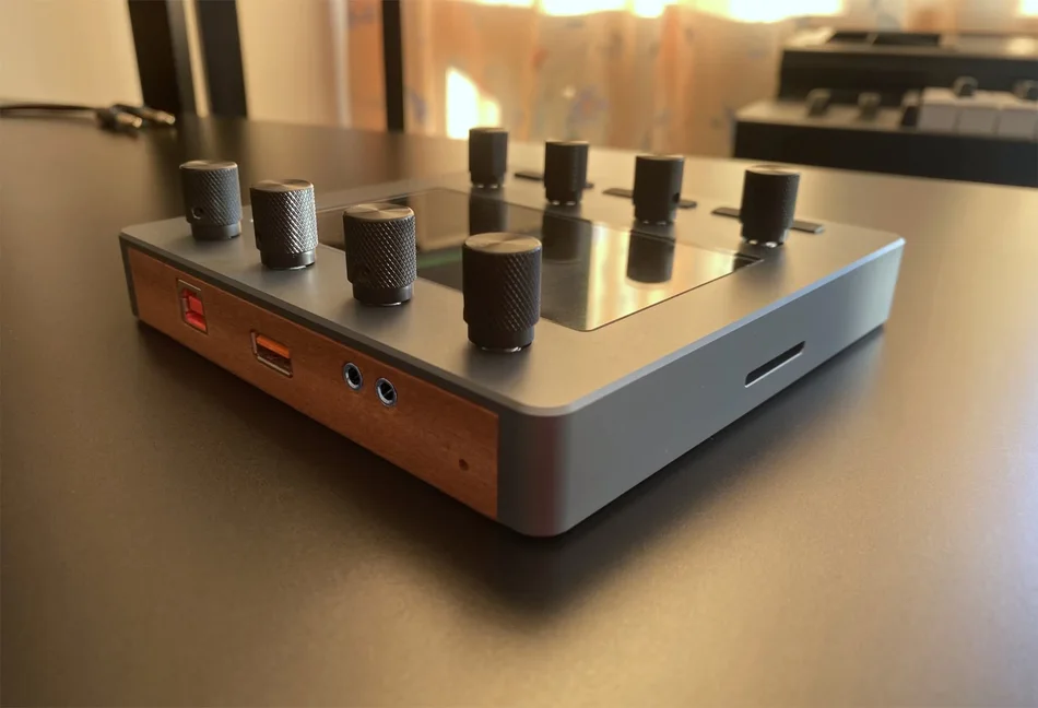 Electra One Mini from a low angle showing the USB and 3.5 mm TRS MIDI sockets in the wooden side
