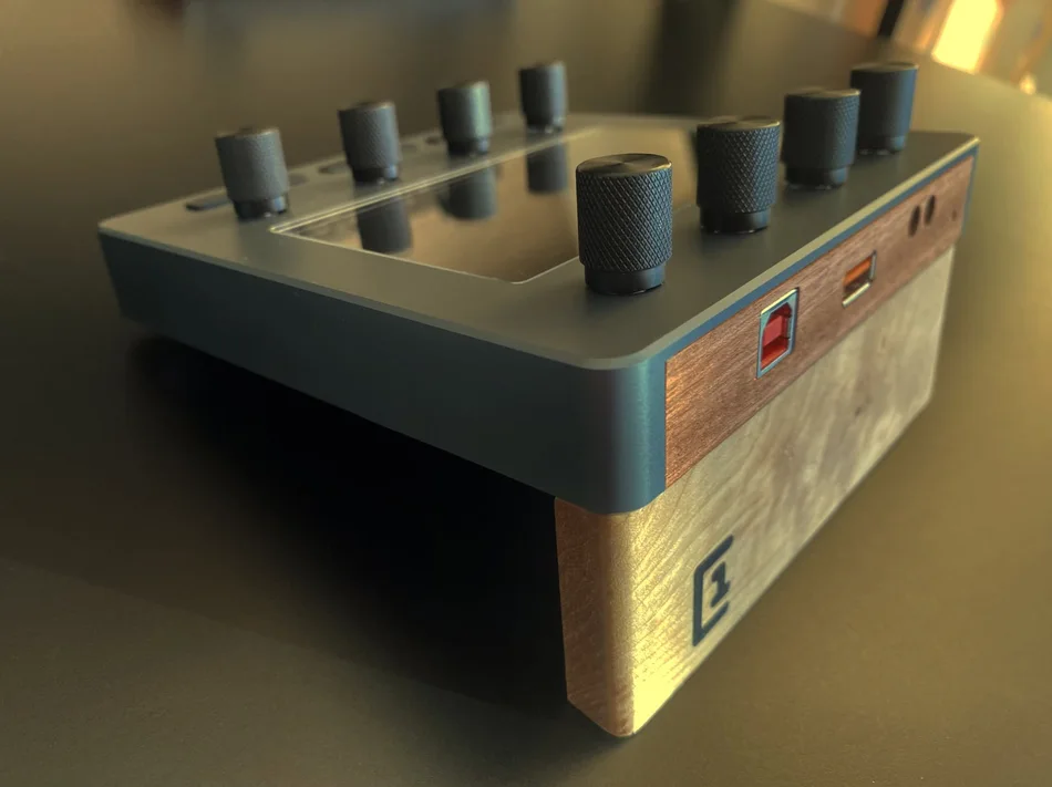 Electra One Mini from the side: knurled metal knobs, a wooden side panel, and the USB and MIDI sockets