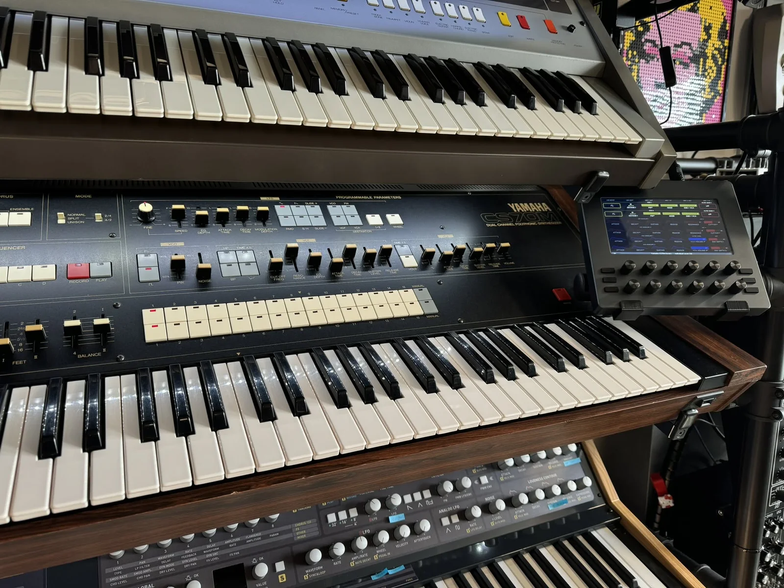 Electra One mk2 on a stand beside a Yamaha CS70M, in a rack of vintage synthesizers