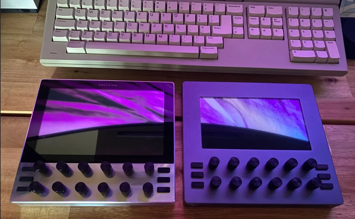 Electra One mk3 beside an Electra One mk2 on a wooden desk, both showing an image on their screens