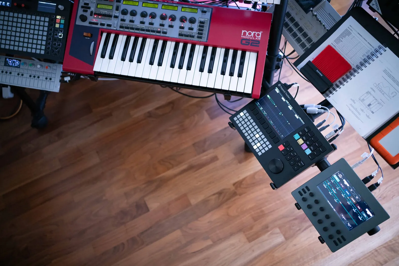 Electra One mk2 on a stand beside a Nord Modular G2 and a groovebox, seen from above on a wooden floor