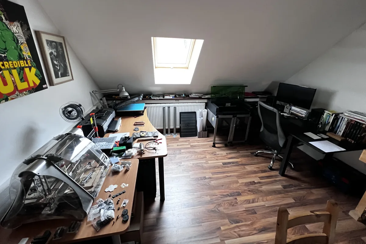 The assembly bench with parts, tools, and a controller enclosure laid out under the skylight
