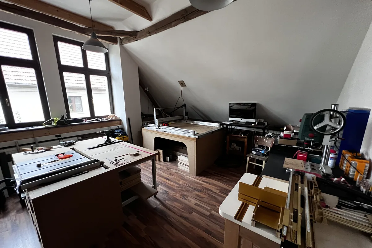 The machine room, with a saw bench, a CNC router, and a drill press under the roof beams