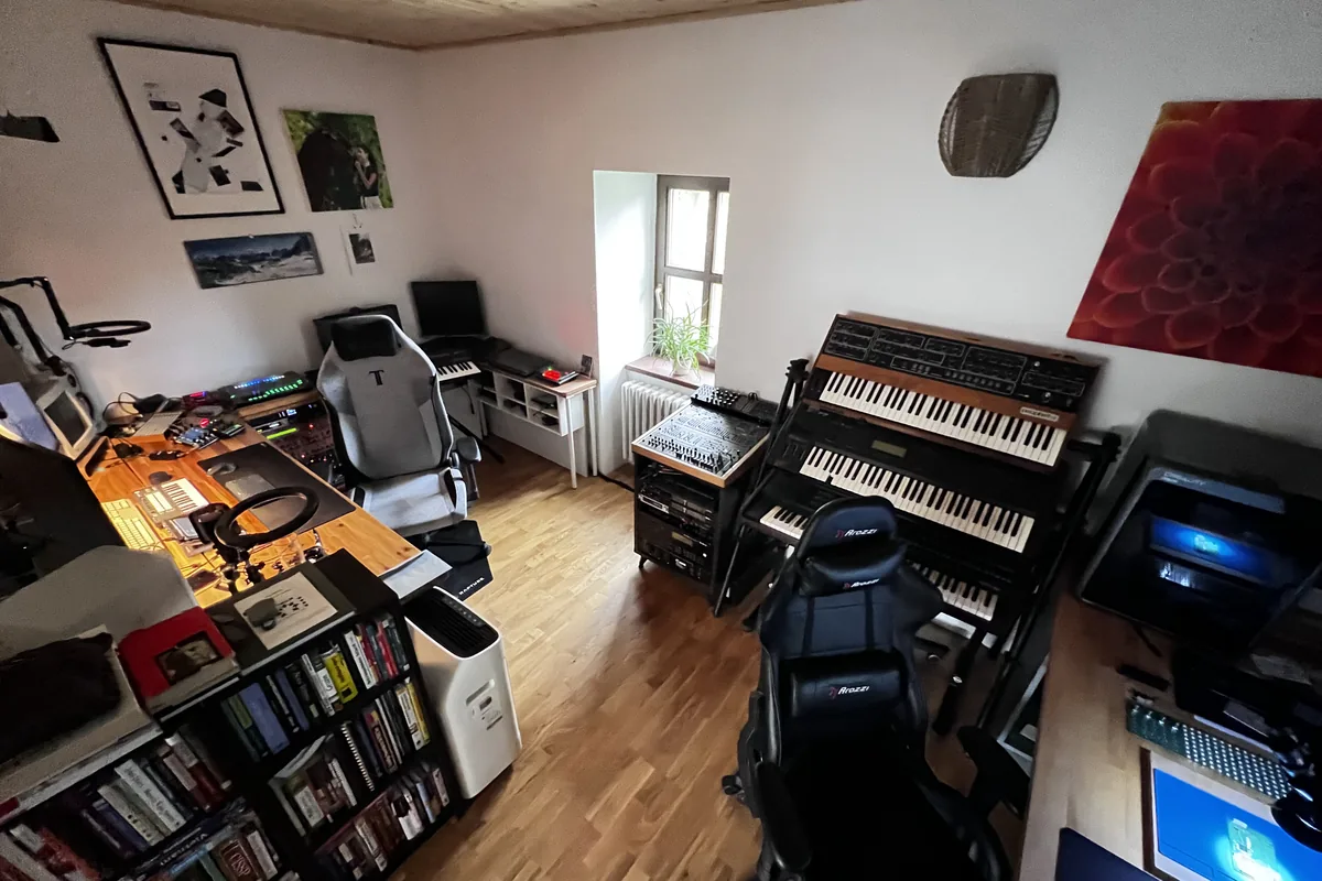 The studio room with synthesizers, keyboards, and a desk of controllers